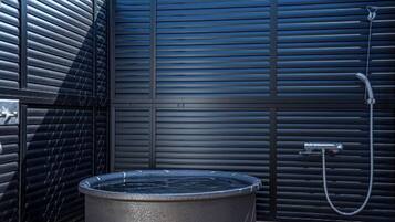 A modern outdoor shower area with a built-in hot tub, a metal faucet, and a hose.