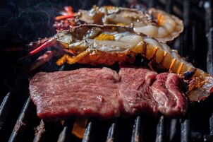Grilled meat and lobster on a grill.