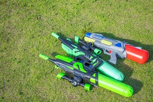 Un juguete de pistola y un juguete de cohete sobre una superficie cubierta de césped.