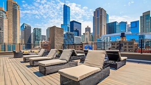 A rooftop lounge with wicker furniture and a city skyline view. - Perfect Destination! Onsite Bar and Restaurant, Close to Shedd Aquarium (Chicago)