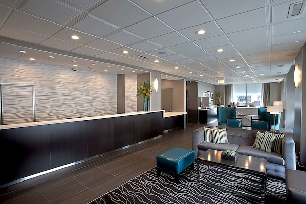 A modern lobby with a reception desk, seating area, and a view of the kitchen. - Perfect Destination! Onsite Bar and Restaurant, Close to Shedd Aquarium (Chicago)