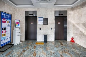 An elevator area with two elevators, a fire alarm, and a self-service kiosk. - Hotel signature (Yangsan-si)