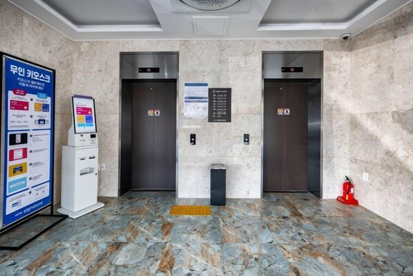 An elevator area with two elevators, a fire alarm, and a self-service kiosk.