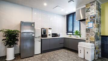 A modern kitchen with a refrigerator, microwave, and coffee maker.