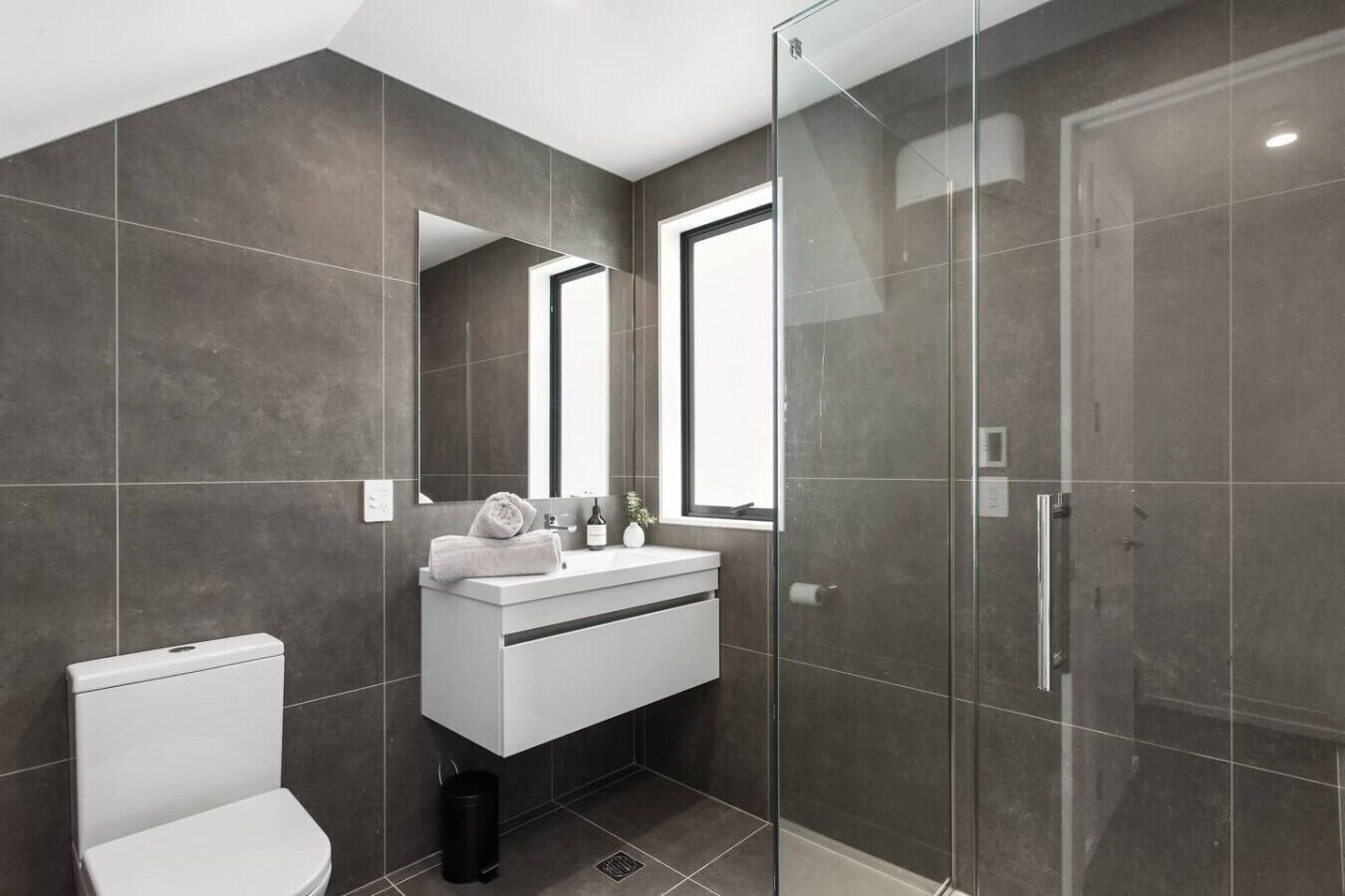 Ein modernes Badezimmer mit Toilette, Waschbecken und einer Duschkabine aus Glas.
