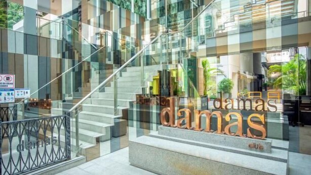 A modern hotel lobby with a glass staircase, a reception desk, and a sign that reads "damas." - Carlton, Chelsea at Plaza Damas 3, Sri Hartamas by COBNB (Kuala Lumpur)