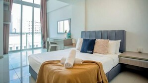 A hotel room with a large bed, a desk, and a view of the city. - Carlton, Chelsea at Plaza Damas 3, Sri Hartamas by COBNB (Kuala Lumpur)