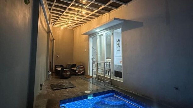 A narrow hallway with a small pool area, a door leading to a balcony, and a ceiling with a grid pattern. - Villa Sunrise F1 (Dau)