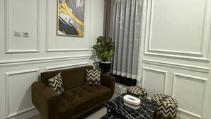 A living room with a brown sofa, a black and white patterned coffee table, and a painting on the wall. - Villa Sunrise F1 (Dau)