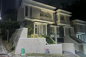 A modern two-story building with a balcony, a staircase, and a well-maintained garden area. - Villa Sunrise F1 (Dau)