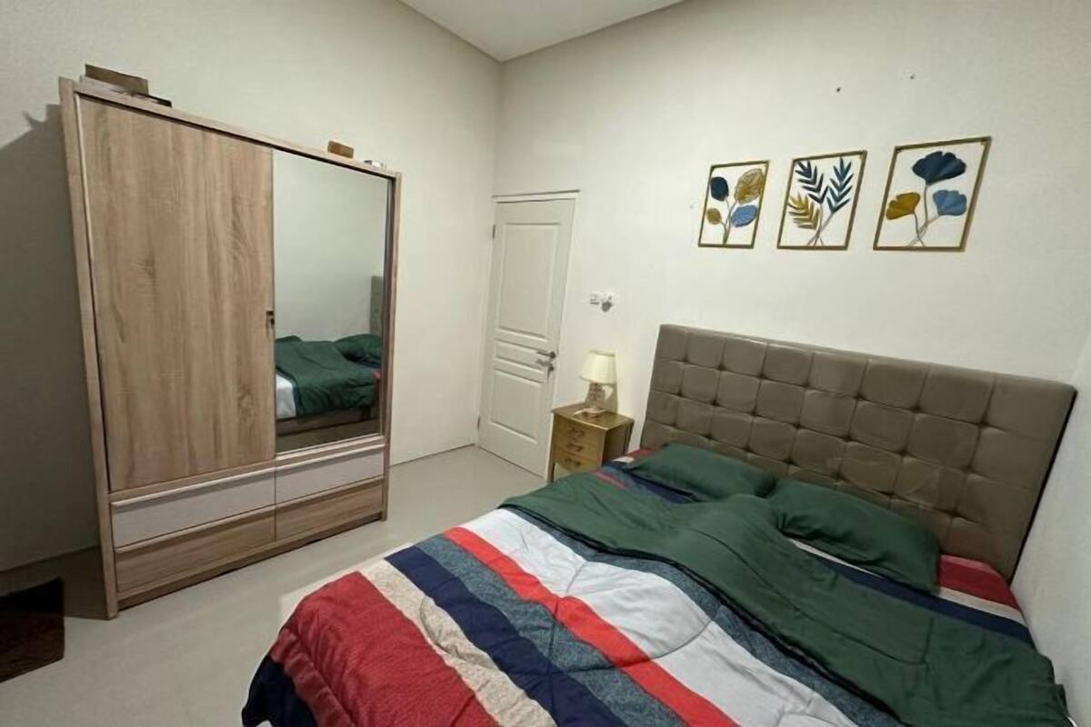 A bedroom with a bed, a wardrobe, a bedside table, and wall art.