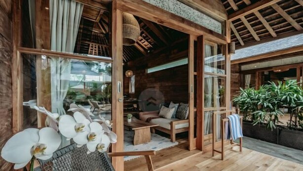 A wooden cabin with a cozy interior, featuring a sofa, a dining table, and a chair. - KAJU Villa Canggu (Bali)