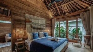 A wooden room with a bed, a small table, and a chair. - KAJU Villa Canggu (Bali)