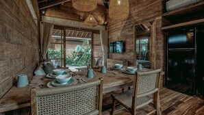 A wooden interior with a dining table set for four, wicker chairs, and hanging woven light fixtures. - KAJU Villa Canggu (Bali)
