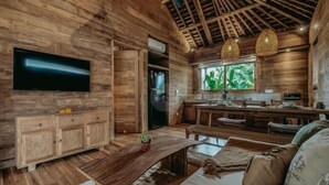 A rustic wooden interior with a flat-screen TV, a wooden cabinet, a dining area, and a sofa. - KAJU Villa Canggu (Bali)