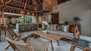 A spacious living area with a wooden ceiling, wicker furniture, a sofa set, and a dining table. - KAJU Villa Canggu (Bali)