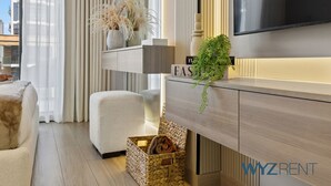 Un salon moderne comprenant un téléviseur à écran plat, un canapé, un banc rembourré, un meuble en bois et un panier en osier.