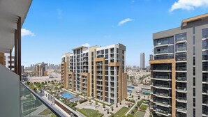 Un immeuble résidentiel de grande hauteur, doté de nombreux balcons, d’une piscine et offrant une vue sur le paysage urbain.