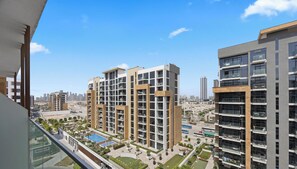 A high-rise residential building with multiple balconies, a swimming pool, and a view of the cityscape.