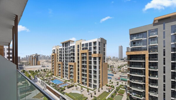 A high-rise residential building with multiple balconies, a swimming pool, and a view of the cityscape. - WYZ RENT|Newly Listed Boho Studio Azizi Riviera26 (Dubai)
