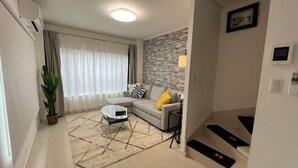 A modern living room with a sofa, coffee table, and a potted plant. - Relax House (Tokyo)