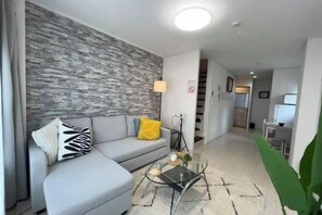 A modern living room with a grey sofa, a glass coffee table, and a patterned rug. - Relax House (Tokyo)