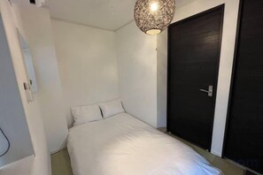 Una camera da letto con un letto, una porta e una lampada a sospensione.