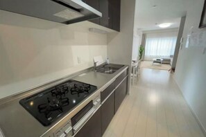 A modern kitchen with a gas stove, stainless steel appliances, and a clean, minimalist design. - Relax House (Tokyo)