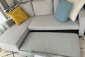 Un divano componibile con un cuscino, un cuscino giallo geometrico e un cuscino azzurro fantasia.