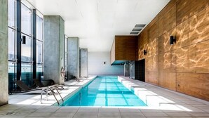 A swimming pool with clear water, surrounded by glass walls and wooden paneling.