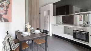 A modern kitchen with white cabinets, a built-in oven, and a dining area with a table set for two. - A Spacious 2BR Apt, Walk to Southern Cross Station (Melbourne)