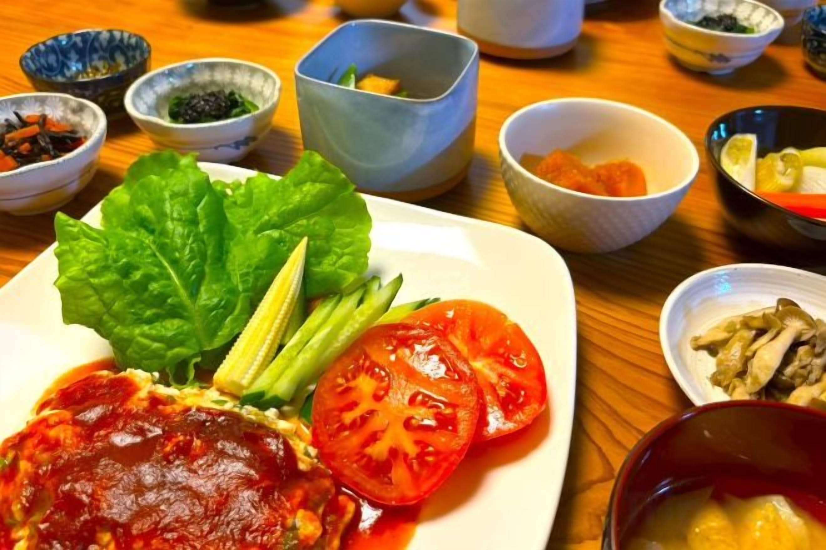 A dining table with various dishes including a plate with lettuce, corn, and tomato, and several small bowls with different food items.