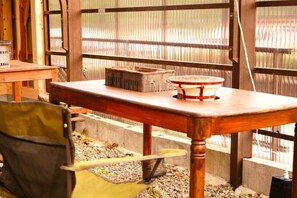 A wooden table with a red tray, a chair, and a window with a metal grid. - chambre d'hôte chaton (Taiki)