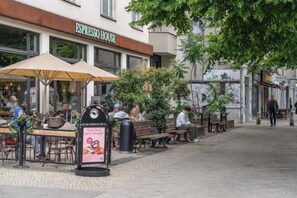Un espacio al aire libre con mesas y sombrillas, un letrero de ESPRESSO HOUSE, y un sendero para peatones.