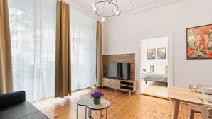 Un salon moderne comprenant un canapé, une table basse agrémentée de fleurs, un téléviseur et un coin repas avec une table et des chaises.