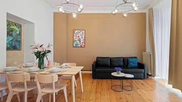 Ein modernes Wohnzimmer mit Essbereich, ausgestattet mit einem schwarzen Sofa, Holzböden und einer Chandeliebre.