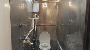 A compact, metallic bathroom with a toilet, a shower, and a small sink. - Shiv Kashi Paying Guest House (Varanasi)