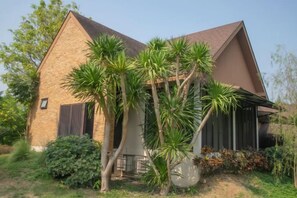 A single-story house with a sloped roof, a brick exterior, and a small porch with a railing. - THAN Getaway Cottage: Private Lake, Pakchong, 2-8+ (Pak Chong)