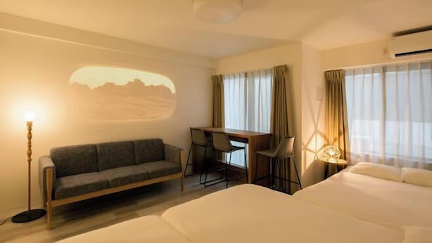 Ein Hotelzimmer mit einem Bett, einem Schreibtisch, einer Couch und einem an der Wand montierten Projektor.