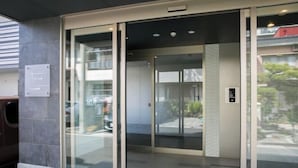 Ein moderner Hotel Eingang mit Glastür, Schild und Fliesenboden.