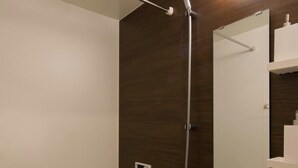 Ein modernes Badezimmer mit Dusche, Spiegel und einem weißen Ablagefach mit Toilettenartikeln.