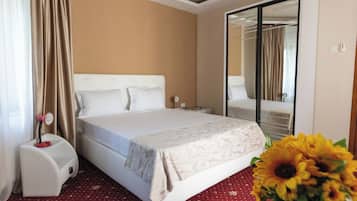 A hotel room with a bed, a nightstand, a mirror, and a red carpet.