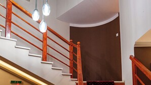 Una scala con ringhiere in legno e un pianerottolo rivestito di tappeto rosso.