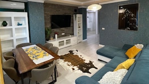 Un soggiorno moderno con un divano, un tavolo da pranzo e una televisione.