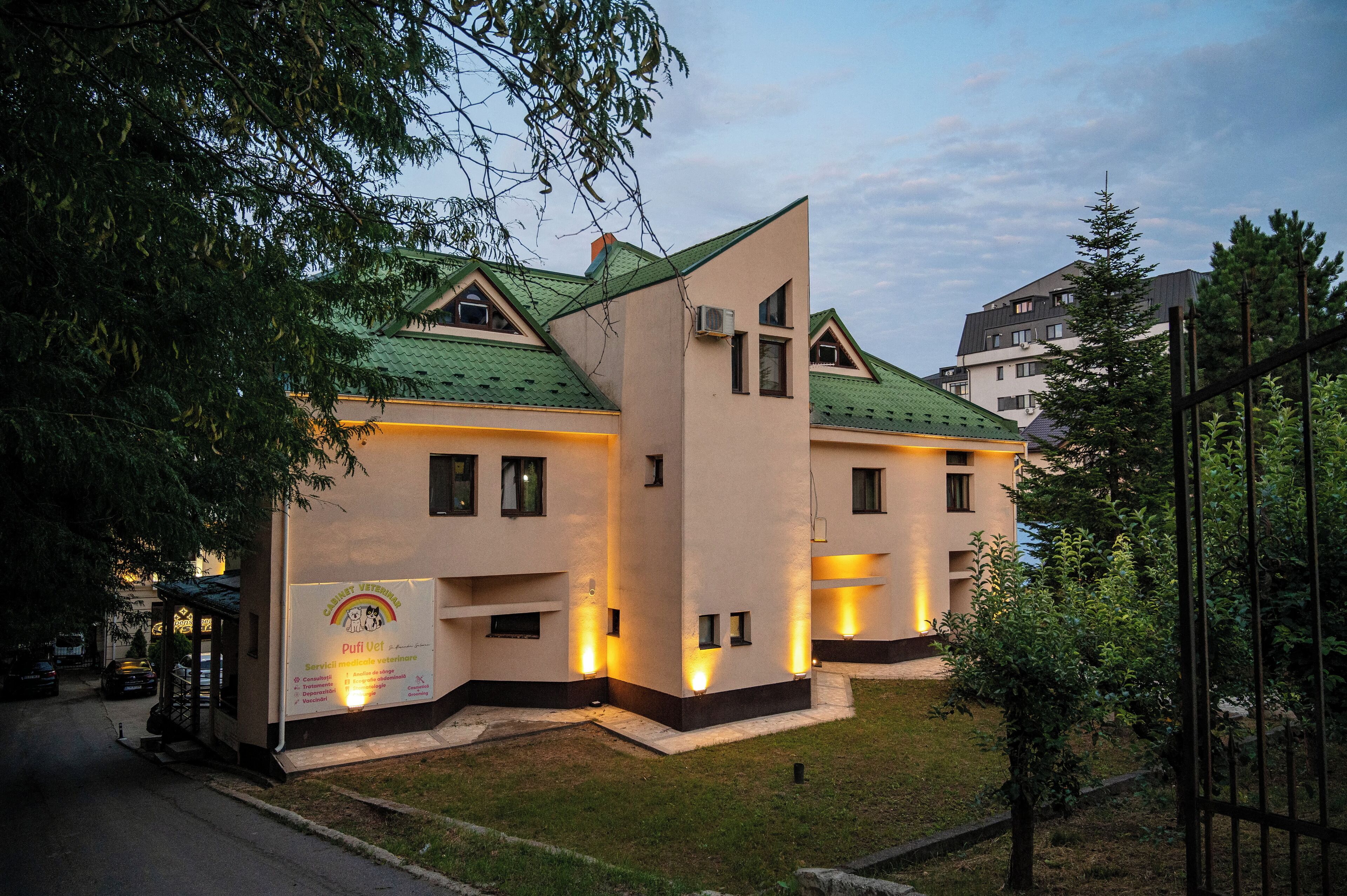 Un edificio moderno con tetto verde, numerose finestre e un cartello che indica una clinica veterinaria.