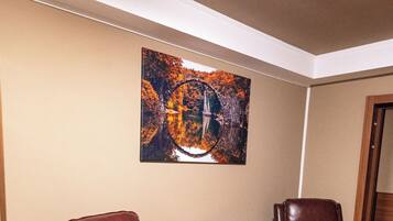 A room with two leather chairs, a round table, and a painting on the wall.
