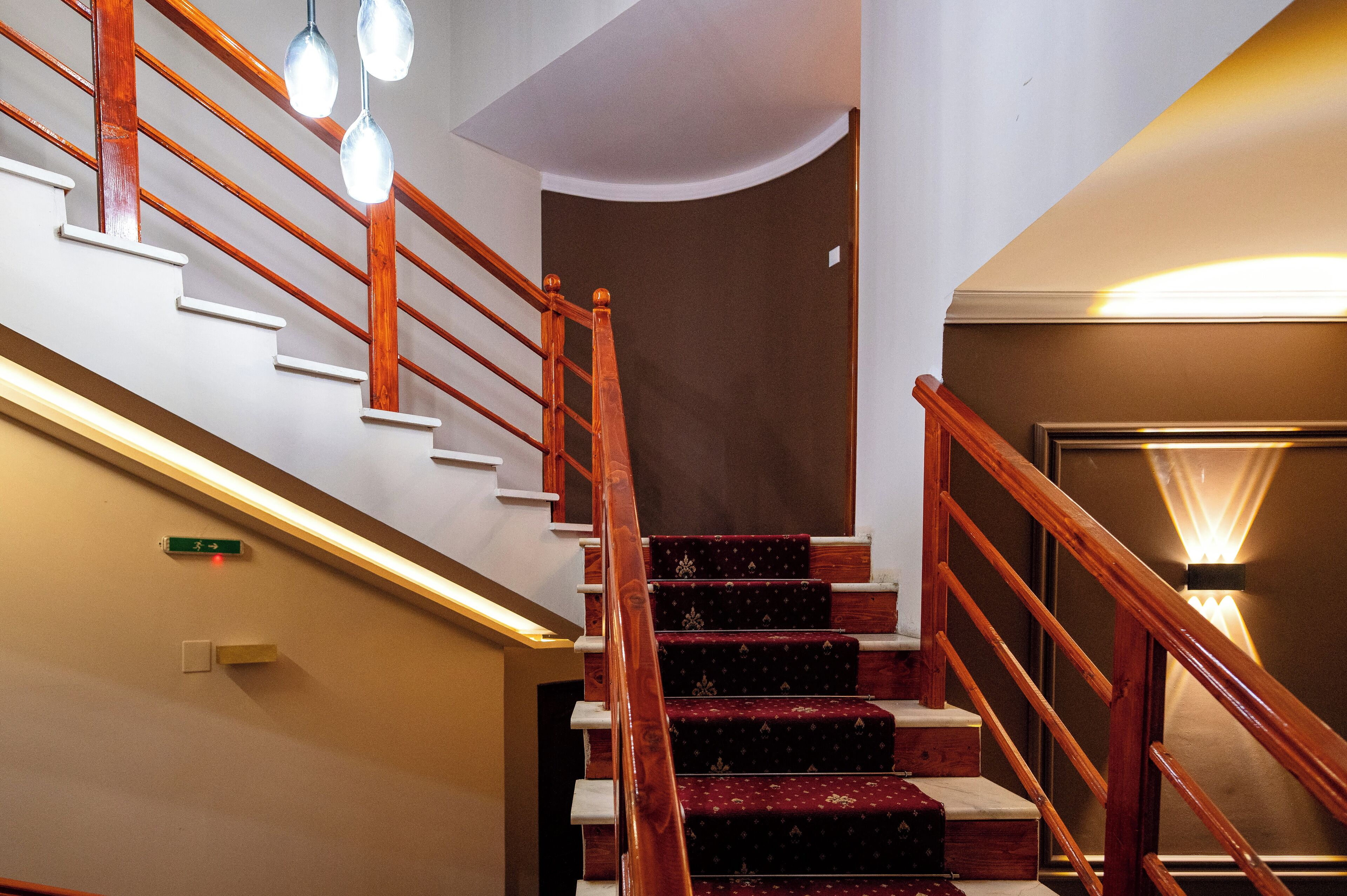 Una escalera con barandillas de madera y un rellano cubierto de alfombra roja.