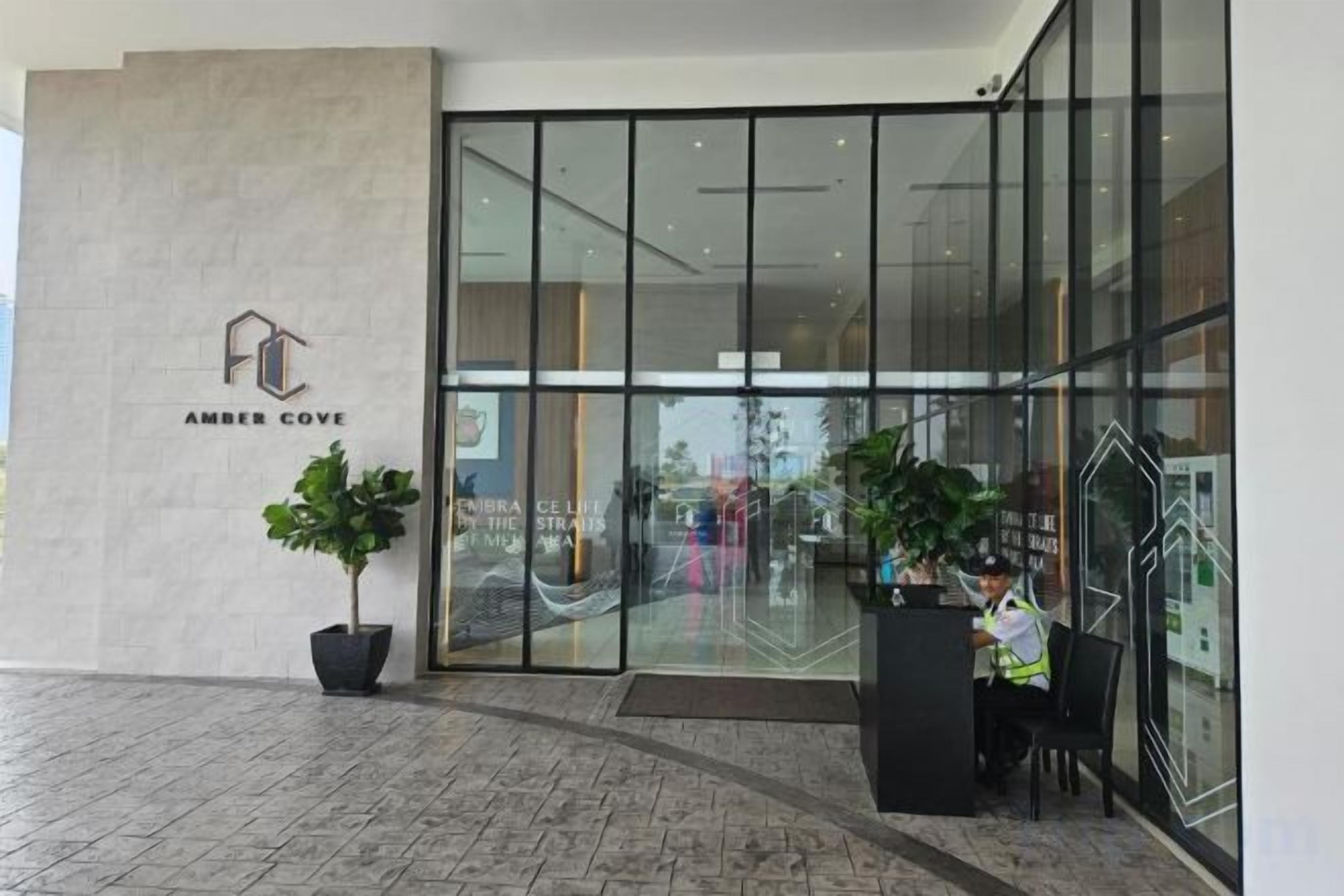 A hotel entrance with a reception desk, a potted plant, and a sign reading 'AMBER COVE'.