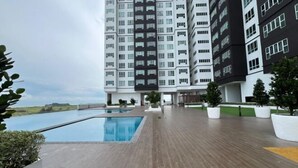 A modern apartment building with a rooftop pool, surrounded by potted plants and a wooden deck. - Amber Cove Melaka Sea view town (Melaka Tengah)