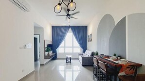 A modern living room with a dining area, a ceiling fan, and a large window with blue curtains. - Amber Cove Melaka Sea view town (Melaka Tengah)